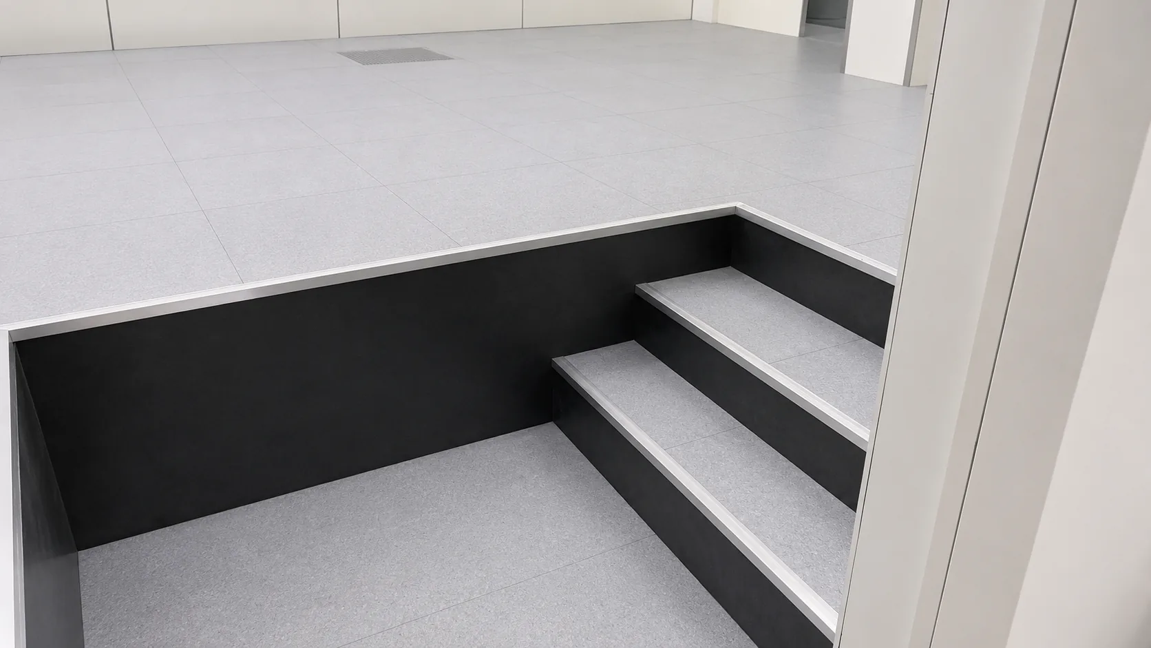 Maatwerk antislip trap bij verhoogde vloer in industriële omgeving, geleverd door Anomalie System Floors