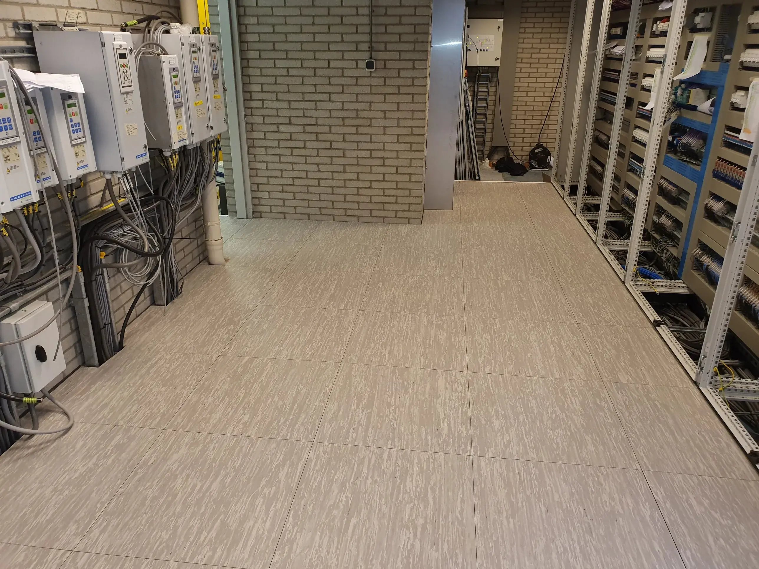 Systeemvloer in een industriële schakelruimte met frequentieregelaars en besturingskasten, door Anomalie